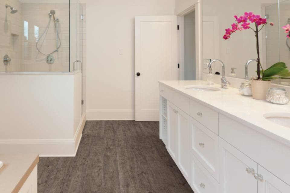 brown toned luxury vinyl flooring in bathroom with shower and vanity.